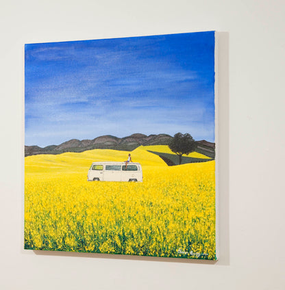 Original painting of a man sitting on the roof of a white campervan on a sunny day of blue skies in yellow flower fields with trees and hills in the background.
